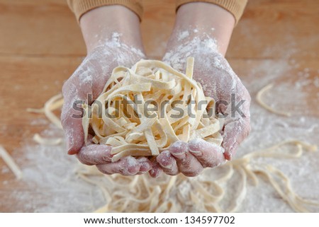 Hands doing fresh italian pasta in wooden background/ Raw fresh spaghetti