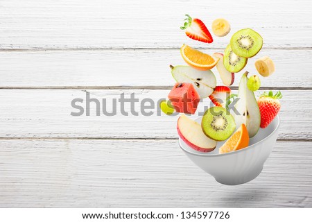 Assorted fresh fruits flying in a bowl/ Light salad with flying fresh fruits