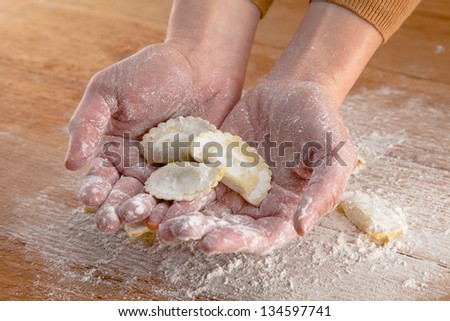 Hands doing fresh italian pasta in wooden background/ Raw fresh pasta