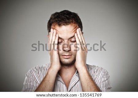 Stressed normal man over grey background. / Young man with eyes closed under stress.