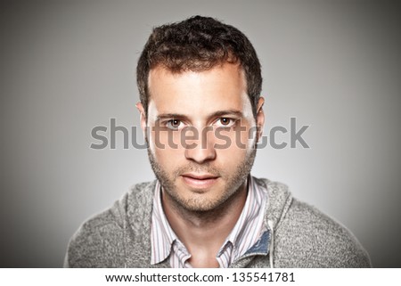Portrait of a normal boy over grey background. / Attractive young man in studio looking at camera