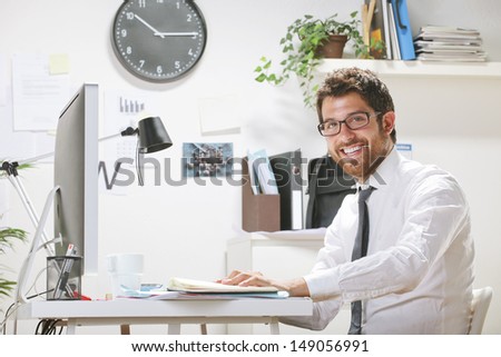 Young businessman in office looking at camera. Businessman with rimmed glasses working.