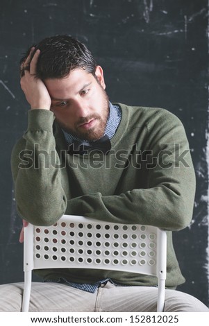 Stressed stylish teacher man in front a blackboard. The teacher.