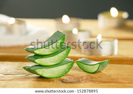 Fresh aloe vera slices on wooden with some candles. Aloe vera plant for skincare therapy.
