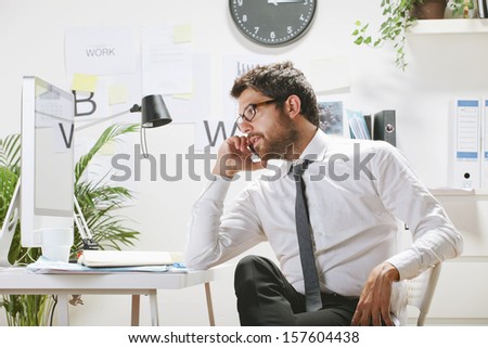 Businessman with rimmed glasses looking at computer./ Young businessman talking on smartphone in office