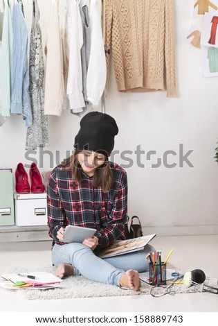 Young creative woman sitting in the floor./ Casual blogger woman working digital tablet in fashion office.
