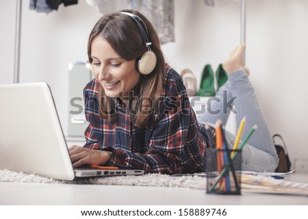 Young Creative Woman Stretched In The Floor And Listening Music. / Casual Blogger Woman Working With Laptop In Her Fashion Office.