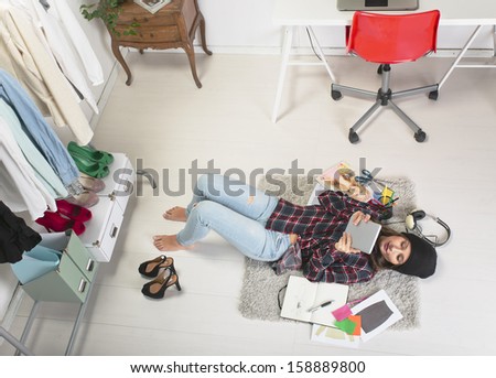 Young creative woman stretched in the floor with digital tablet./ Casual blogger woman working in her fashion office.
