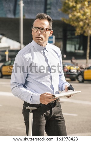 Handsome man in the middle of the street./ Businessman standing with newspaper on the city.