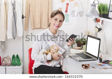 Young Fashion Woman Sending A Message With Smart Phone./ Fashion Magazine Editor In Her Office.