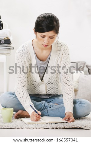 Casual asian woman sitting on the floor and working in home. /  Casual asian woman sitting on the floor and working in home.