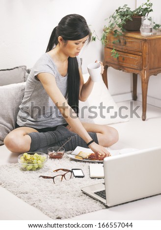 Casual asian woman having breakfast and working in home./ Casual asian woman having breakfast and working in home.