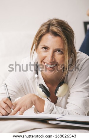Smiling mature woman looking at camera on the bed./ Mature businesswoman working at home.