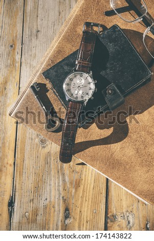 Man wristwatch, calendar, key and glasses on a old table./ Still life on wood background.