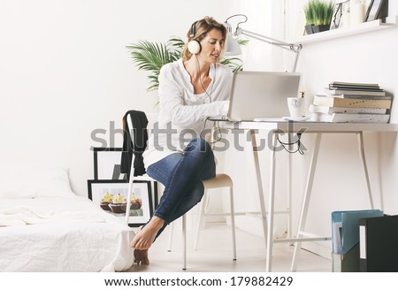 Business woman listening music with headphones./ Beautiful mature business woman working with laptop in home.