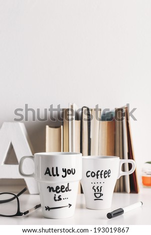 Hipster cup of coffee on a books library./ Two white coffee mug with diy decoration.