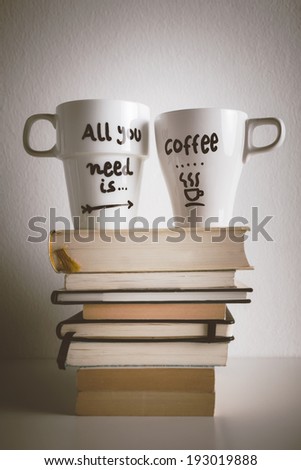 Hipster cup of coffee over a books./ Two white coffee mug with diy decoration on vintage effect.