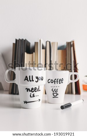 Hipster cup of coffee on a books library./ Two white coffee mug with diy decoration.