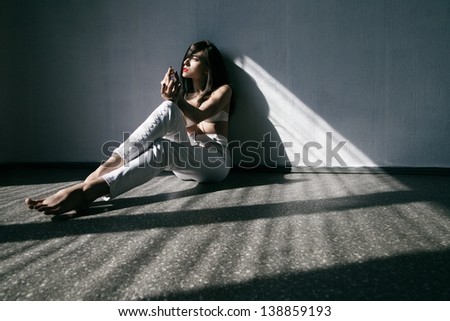 Beautyful woman with long sexy legs wearing white jeans and lingery in sun light through window