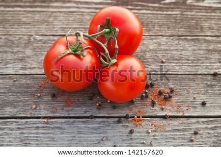Dewy red tomatoes with pepper on old wooden table