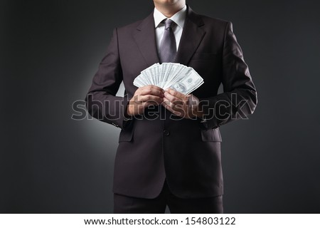 businessman in suit holding money in hands on dark background