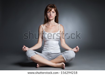 Young woman doing yoga isolated against dark background