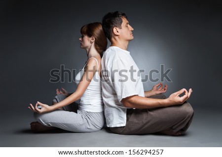 Young healthy couple in yoga position on dark background