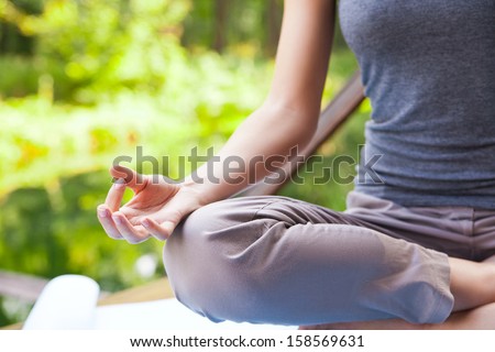 Young girl doing yoga (lotus pose) in the park