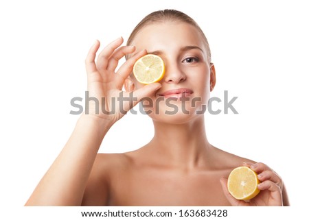 young woman holding lemon slice in front of eye over white background
