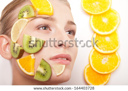 Beautiful young smiling cheerful woman with fruit mask on her face isolated on white background