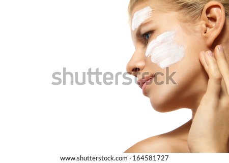 Portrait of young woman applying moisturizer cream on clean fresh face isolated