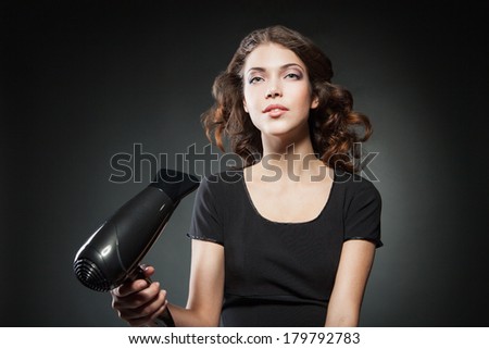 girl dries hair by hairdryer over dark background
