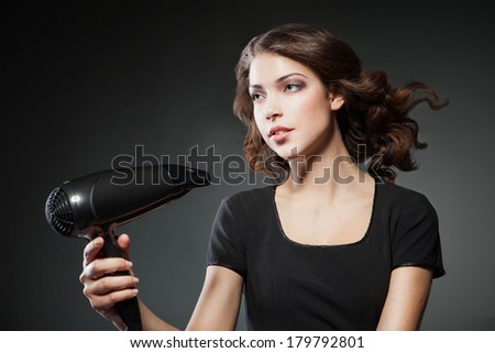 girl dries hair by hairdryer over dark background