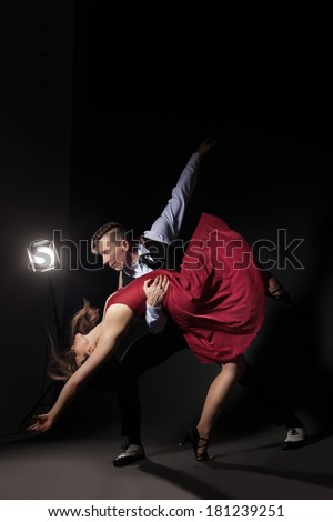 Man and woman in the most romantic dance tango over dark background