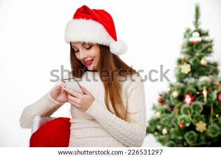 Girl in santa hat call mobile phone by christmas tree Isolated