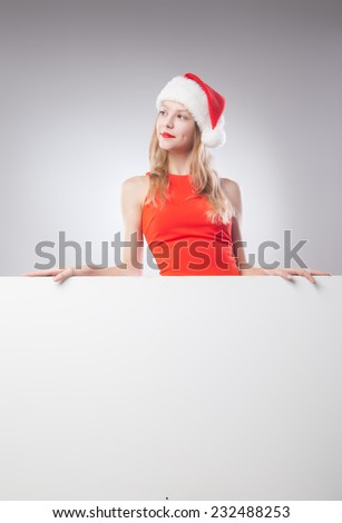 Joyful Beautiful christmas woman in santa hat holding empty board isolated on white background