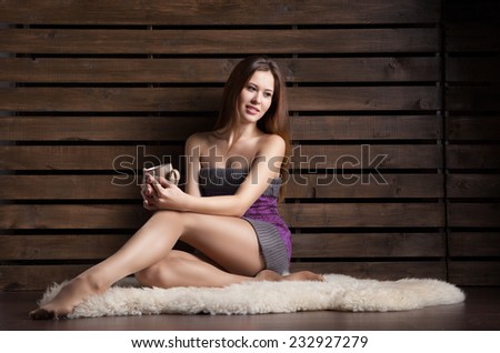 Sexy woman sitting on the floor over wood background with cup of coffee