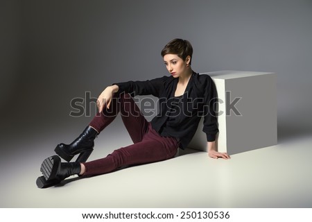 beautiful thin brunette woman  sitting on floor by cube her hand on knee.