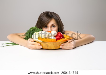 Young woman looking out from cutting board over the gray background.