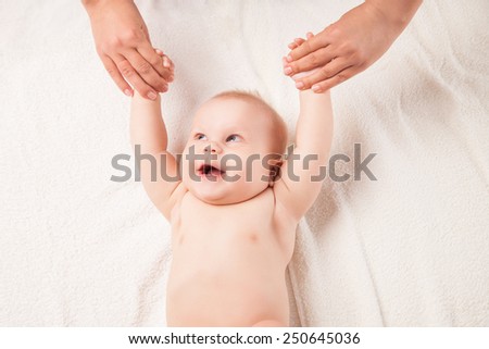 Cute baby lying on white blanket on back, hands lifted.  Half-length, isolated over white background.