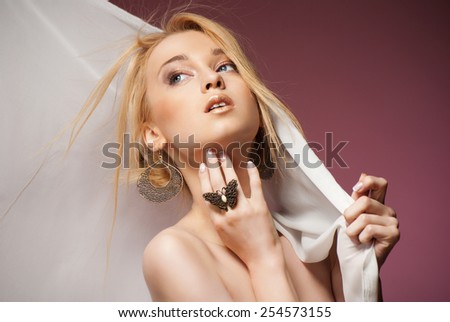 Beautiful Young Woman in waving Chiffon Scarf covering her head. Isolated over pink background.