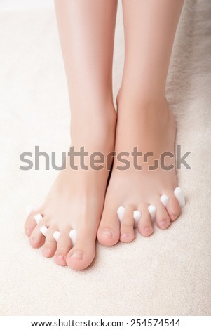 foot pedicure applying woman\'s feet in toe separators white background