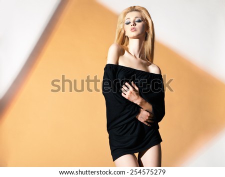 Blonde woman, with black blouse and naked shoulders her hands drawn to chest and stomach