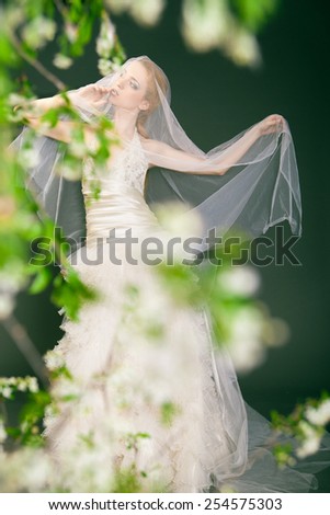 Dreamy beautiful blonde bride walking alone in the park enjoying wind wave and dance