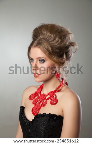 Closeup of beautiful woman with evening make-up and big red necklace. Jewelry and Beauty. Fashion photo