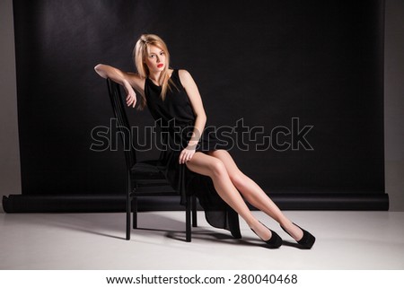 The image of a beautiful luxurious woman sitting on a black chair. Isolated.