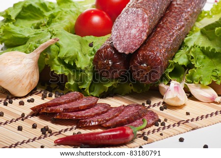 Salami with lettuce, garlic and tomatoes on white background