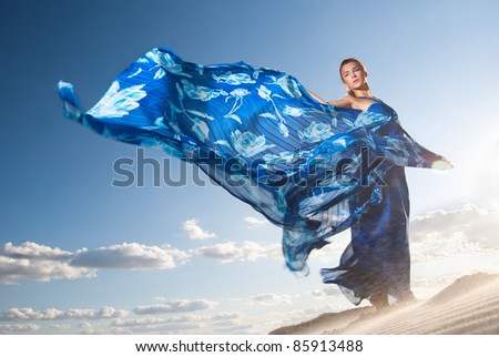 Portrait of a beauty woman in blue dress on the desert