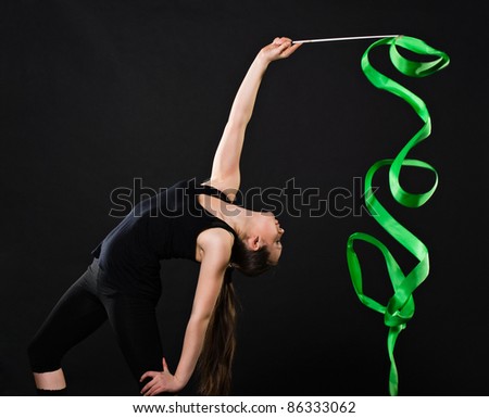 attractive woman dancing with green ribbon against dark background