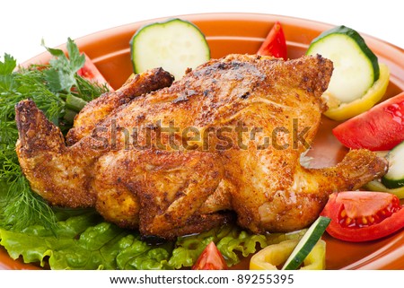 fresh grilled whole chicken with cucumber, raw tomatoes on plate with leaf lettuce isolated over white background